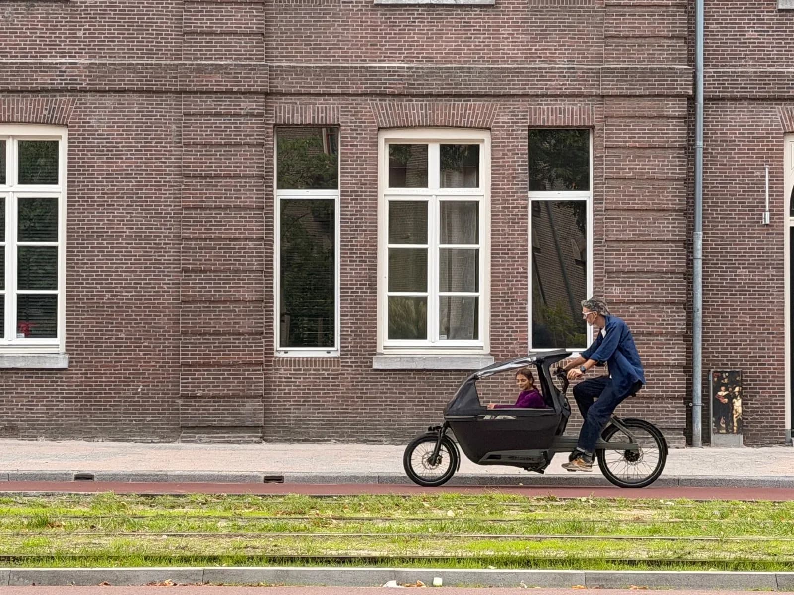 A cargo bike passing a brick facade